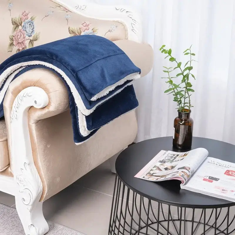 Deep blue and white double-layer lamb fleece blanket with soft sherpa lining draped over ornate armchair