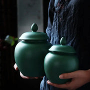 Deep green ceramic tea caddy jars with rounded bodies and oval finial lids for kitchen storage container use