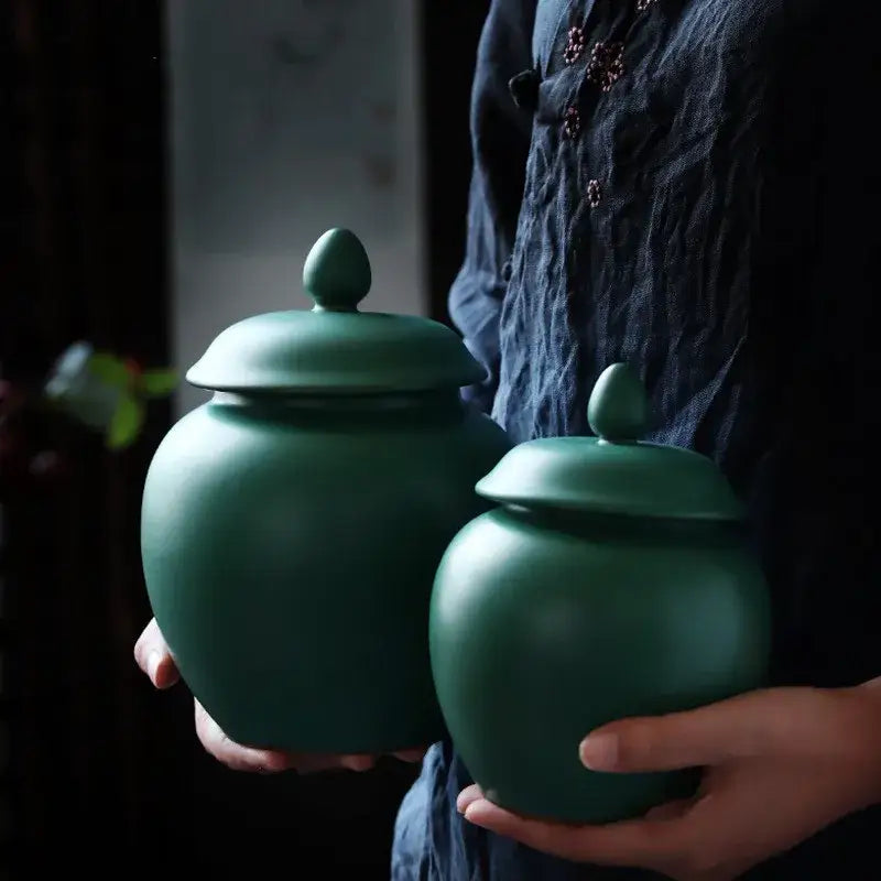 Deep green ceramic tea caddy jars with rounded bodies and oval finial lids for kitchen storage container use