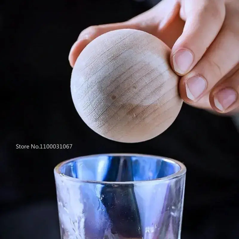 A smooth light-colored wooden sphere with visible grain patterns complementing the diamond crystal glass water set