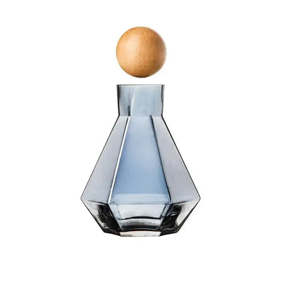 A sleek blue diamond crystal glass water decanter with faceted design and smooth wooden stopper for dining room use