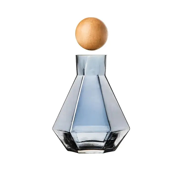 A sleek blue diamond crystal glass water decanter with faceted design and smooth wooden stopper for dining room use