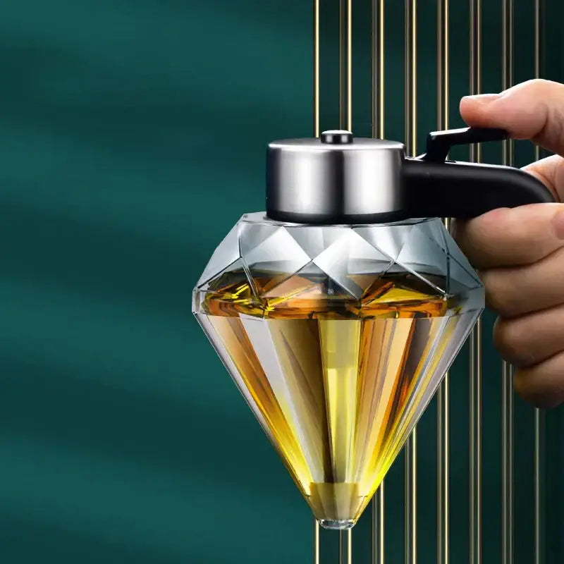 Diamond glass syrup honey dispenser with silver lid and black handle filled with golden-yellow liquid in glass jar