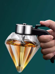 A clear diamond glass syrup honey dispenser with a silver metal lid and black handle for kitchen oil storage