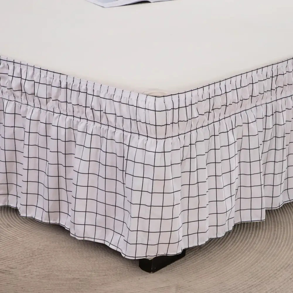 White bed skirt with black diamond lattice ruffled pattern and elastic band for a stylish bedroom decor