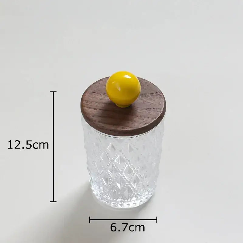 Clear glass jewelry jar with diamond pattern and walnut lid topped by bright yellow decorbites colorful ceramic ball knob