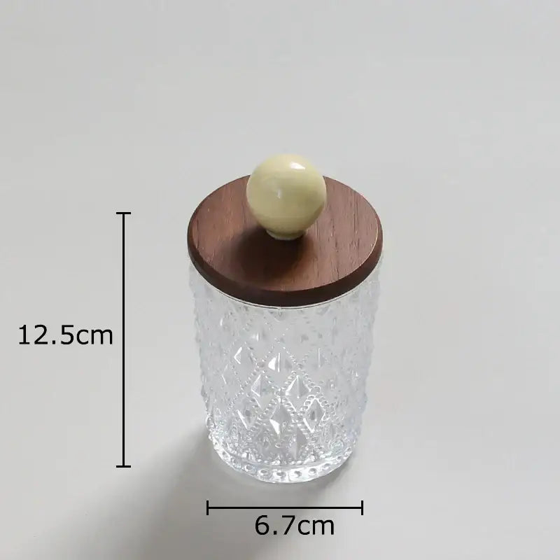 Clear glass jewelry jar with diamond pattern and walnut lid topped by off-white colorful ceramic ball knob