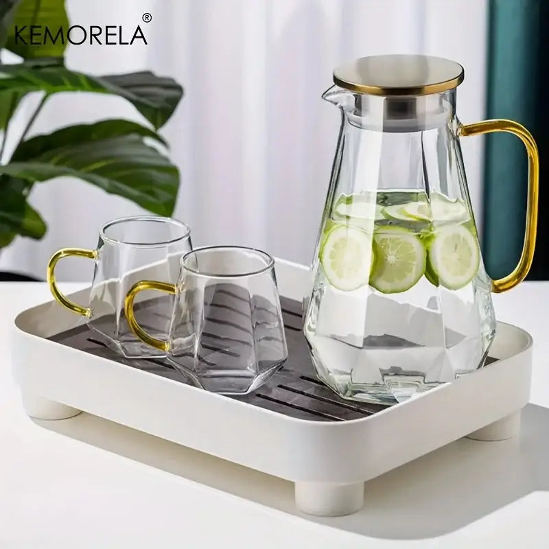 Clear glass teapot with diamond texture and gold-toned lid and handle filled with water and lime slices for dining room