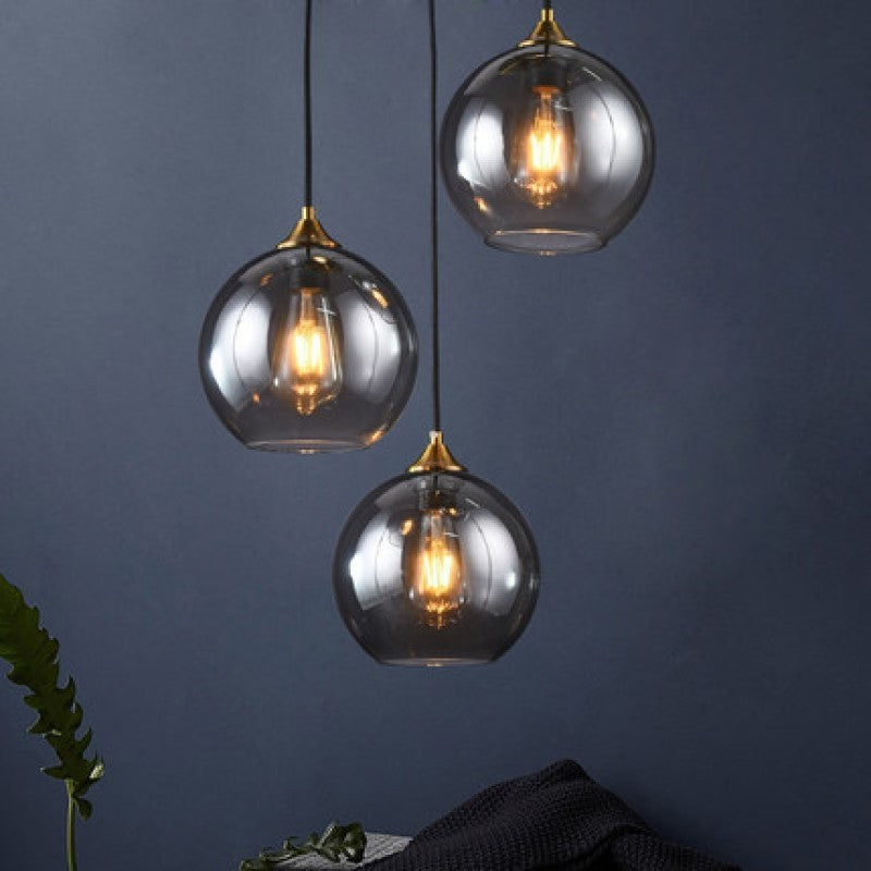 Three glass globe pendant lights with brass accents and edison bulbs.