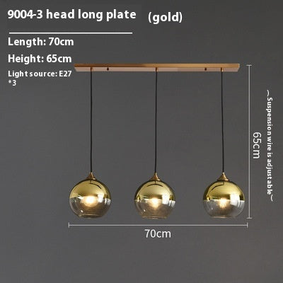 Gold pendant light with three spherical glass shades and a wooden plate.