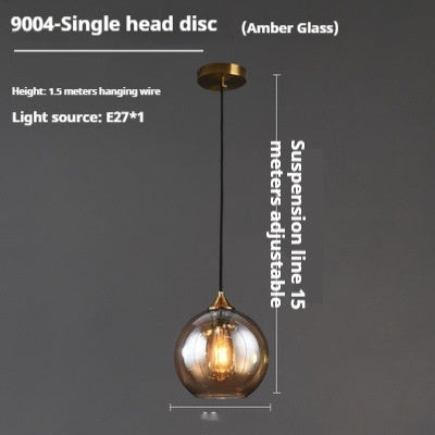 Amber glass globe pendant light with gold accents and adjustable suspension line.
