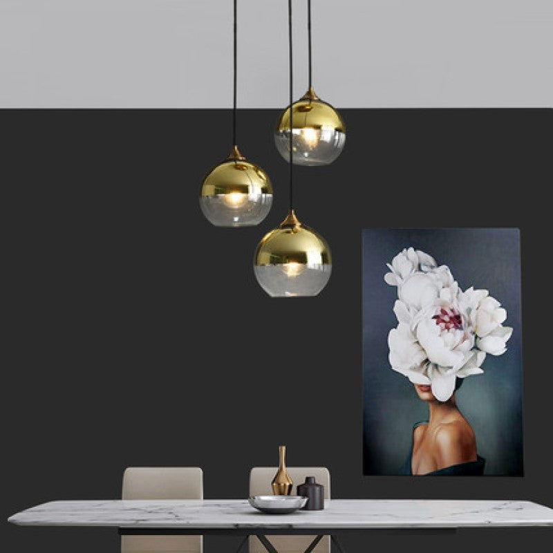 Gold and clear glass globe pendant light set with black cords.