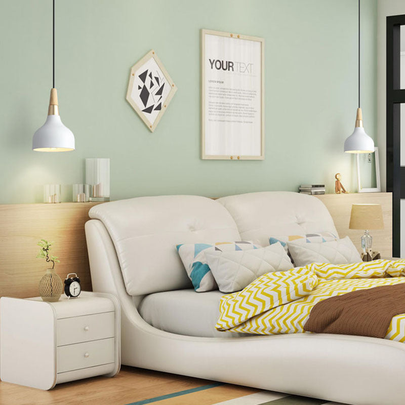 White upholstered bed frame with curved headboard shown alongside a modern dining room chandelier for stylish decor
