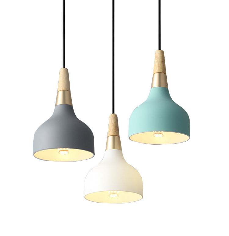 Three pendant lights with wooden accents and black cords, featuring gray, white, teal shades.