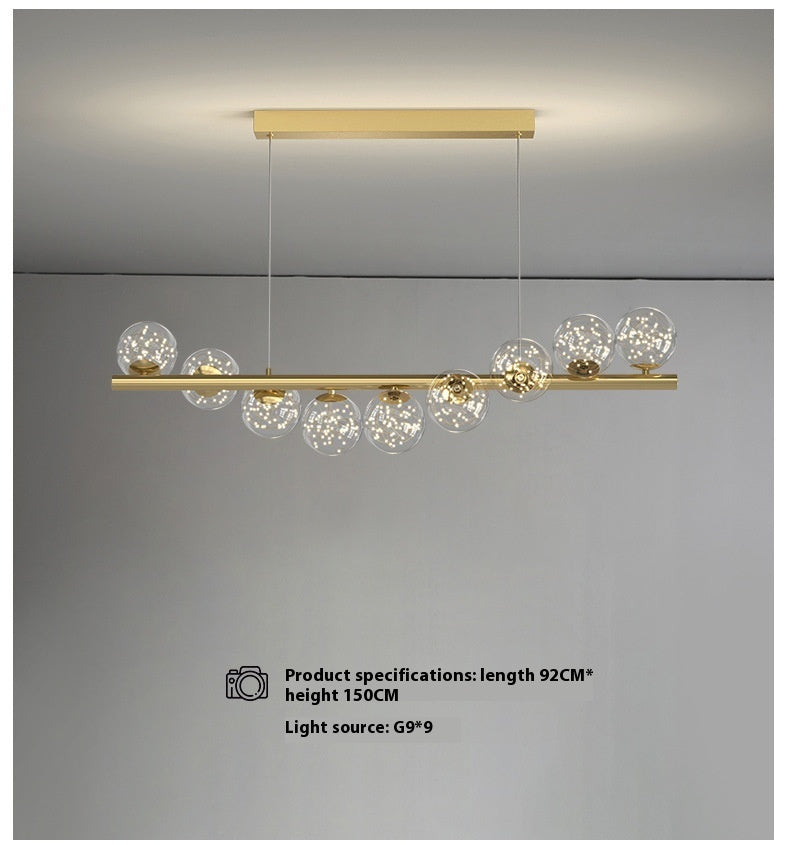 Gold linear pendant light with glass globe accents and modern design.