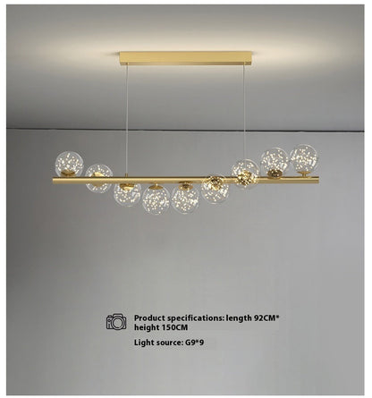 Gold linear pendant light with glass globe accents and modern design.