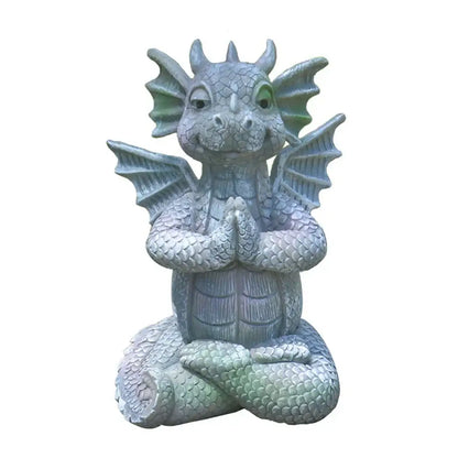 A gray dragon dino garden sculpture with green-tinted wings and eyes meditating for fun dinosaur decorbites dino garden decor