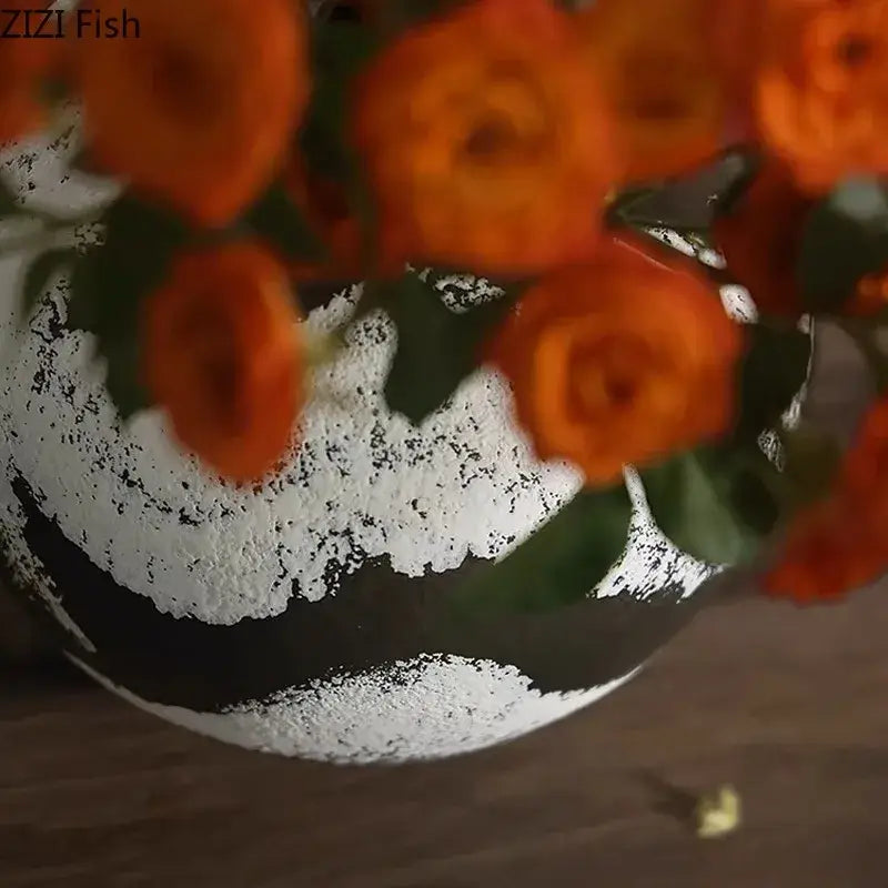 A distressed black and white ink painting ceramic vase holding vibrant orange roses for living room decorbites decor