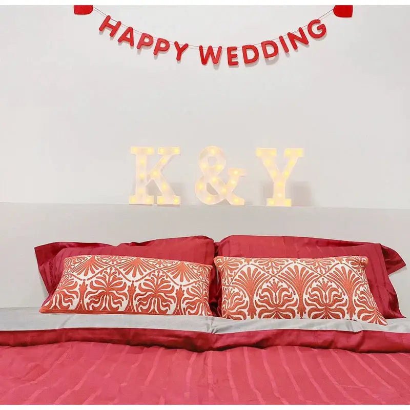 Double happiness embroidered red traditional lumbar pillow with patterned throw pillows featuring a decorative fan design on bed