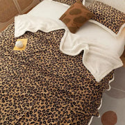 A cozy double layer leopard print coral fleece blanket with plush white lining and scalloped edges for bedroom use