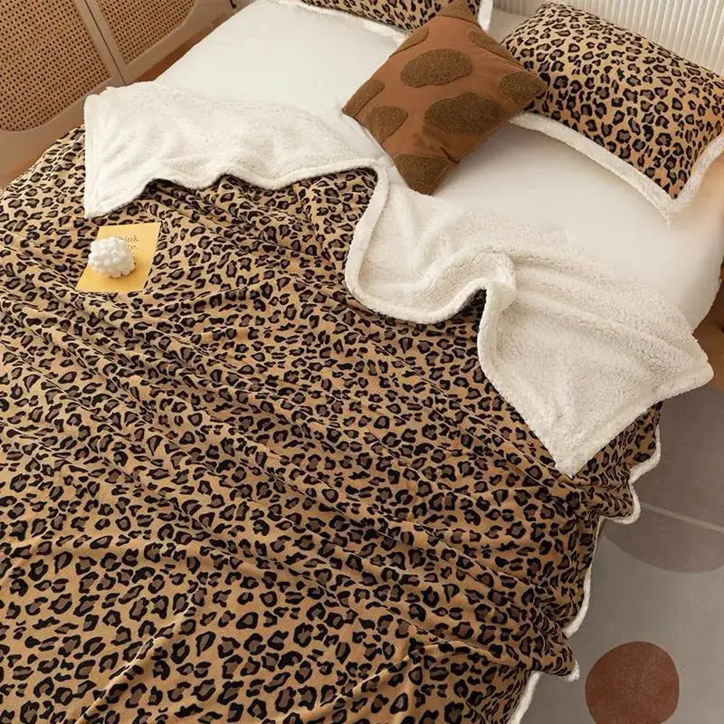 A cozy double layer leopard print coral fleece blanket with plush white lining and scalloped edges for bedroom use