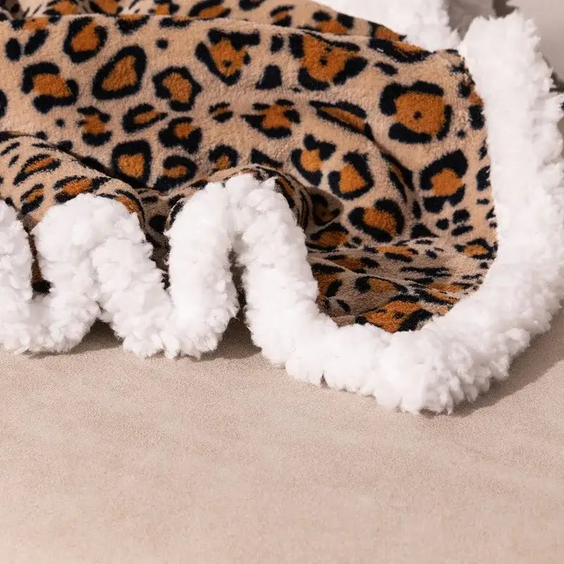 A cozy double layer leopard print coral fleece blanket with plush white faux fur trim for bedroom bedspread