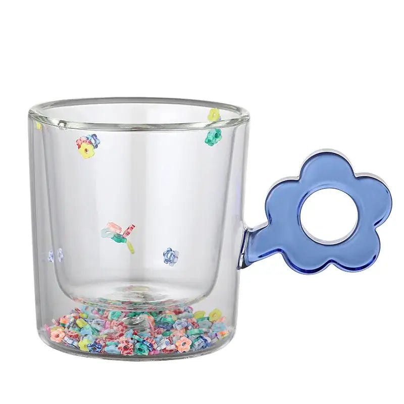 Clear double wall glass mug with blue flower-shaped handle and glitter flowers filled with multicolored beads for kitchen use