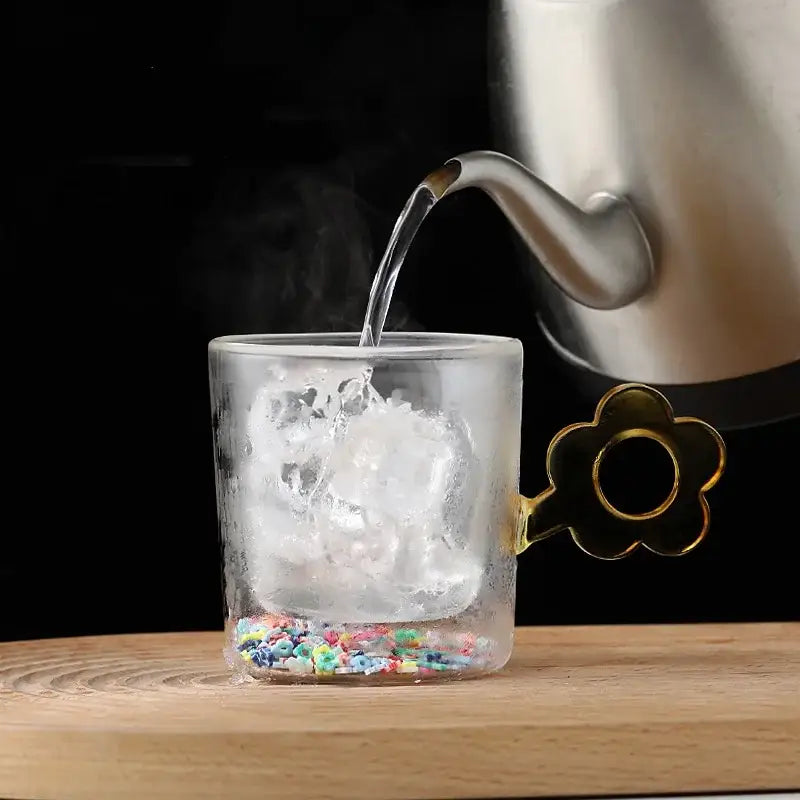 Double wall glass mug with gold glitter flower handle filled with ice and colorful confetti for kitchen use