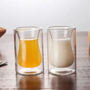 Two clear double-walled glass mugs filled with orange juice and milk from drinkware collection for dining room use