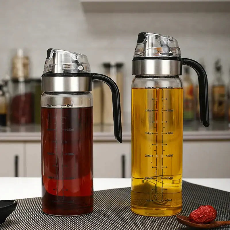 Two durable automatic oil glass dispensers with stainless steel lids in red and gold for kitchen storage