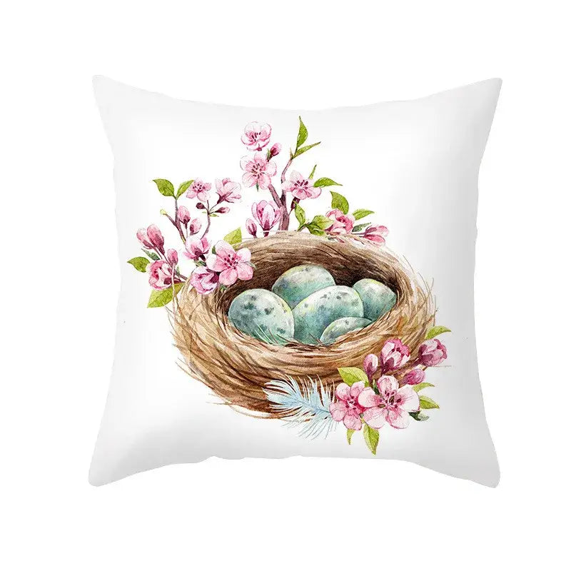 White throw pillow with watercolor woven nest and speckled eggs surrounded by pink blossoms for easter rabbit home decor