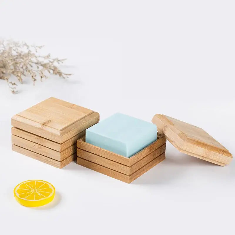 A light blue rectangular bamboo soap rests inside an eco-friendly bamboo soap dish with matching lid bathroom storage rack