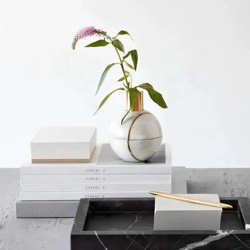 White marble vase with gold-toned rim and circular accent on elegant black and white afralia marble tray bedroom decor