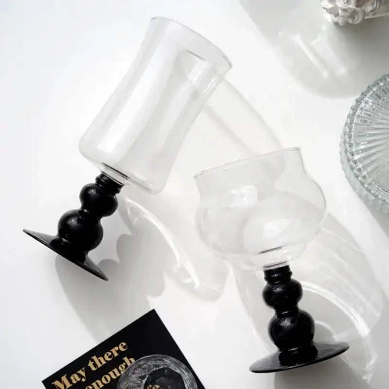 Two clear glass goblets with black bulbous stems and flat bases for elegant black goblet glass coffee use