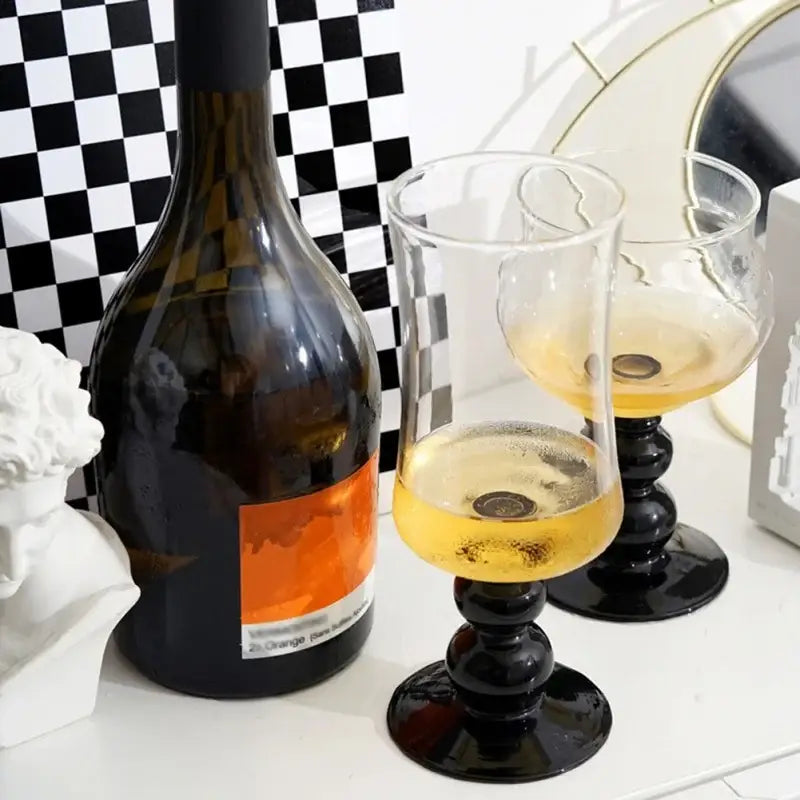 Two elegant black-stemmed goblet glass coffee cups with glossy finish holding golden-hued liquid for dining room use