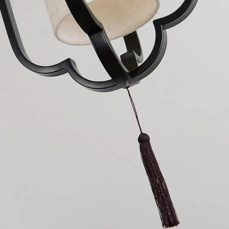 Elegant black wrought iron wall sconce lamp with beige fabric shade and dark brown tassel for bedroom lighting