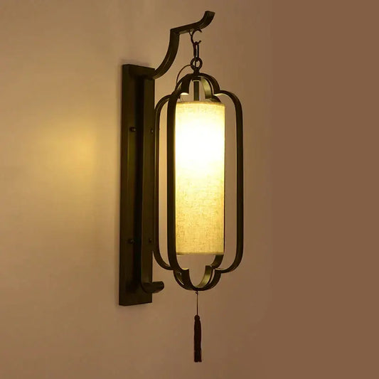 Elegant black wrought iron wall sconce lamp with a warm rectangular fabric shade and a dangling tassel for bedroom lighting