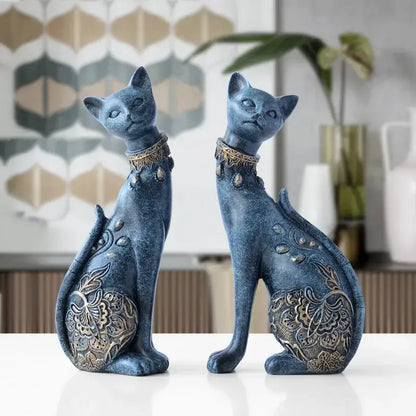 Two elegant blue and gold decorbites cat statues with intricate patterns sitting side by side on a white surface
