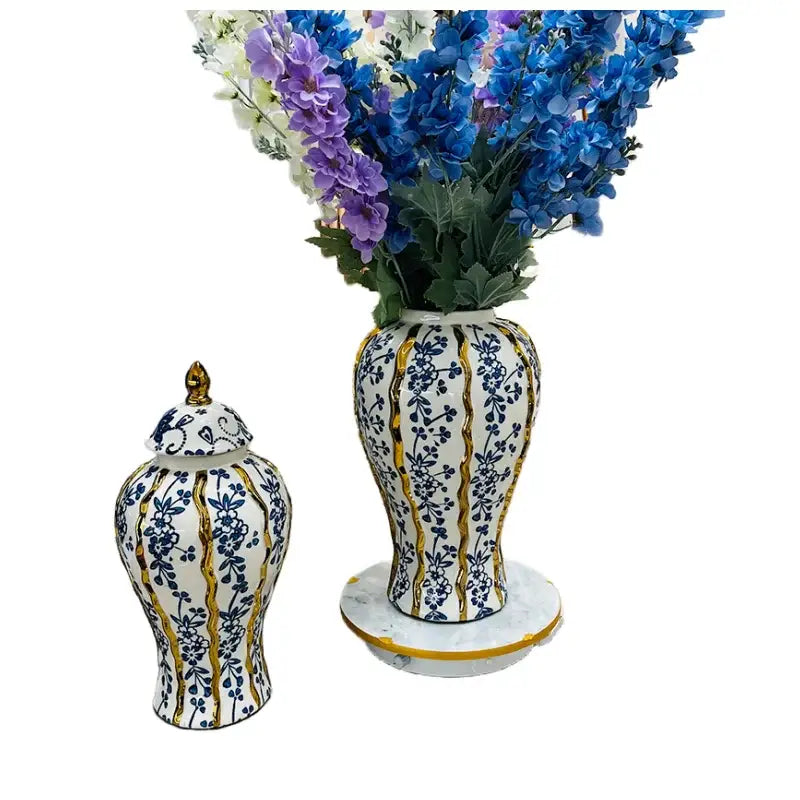 Elegant blue glazed ceramic ginger jar with white base, blue floral patterns, gold vertical stripes, and matching lid finial