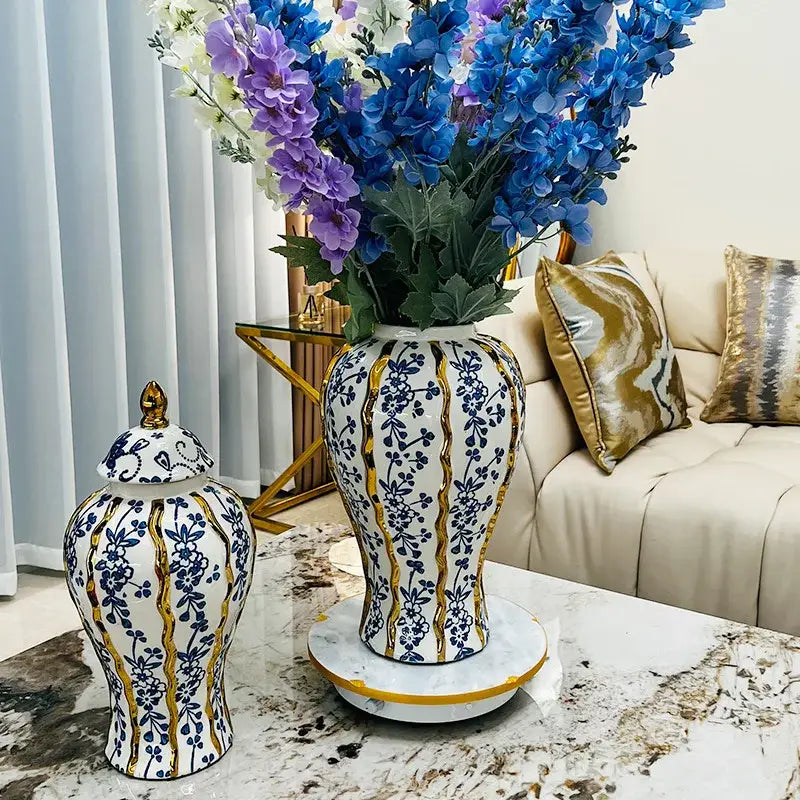 Elegant blue glazed ceramic ginger jar with white ceramic vase blue floral patterns and gold stripes holding purple flowers