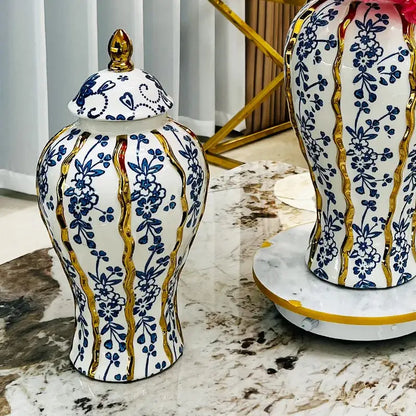Elegant blue glazed ceramic ginger jar with white base, blue floral patterns, gold trim, and matching lid with golden finial