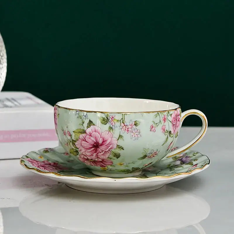 Elegant blue and pink floral porcelain tea cup set with gold-trimmed pink roses on a soft mint green background