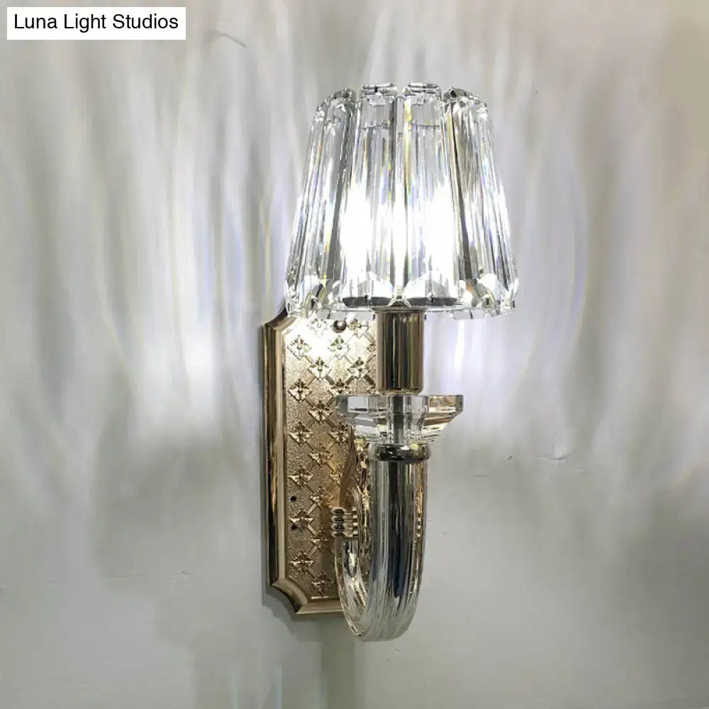 Elegant brass and crystal tapered cone sconce light with clear crystal shade and ornate diamond pattern mounting plate