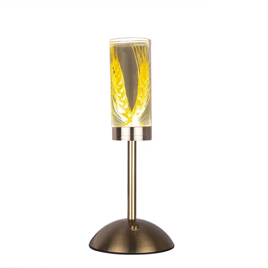 A sleek brass-finished desk lamp with decorbites eternal flower acrylic shade featuring illuminated golden wheat design