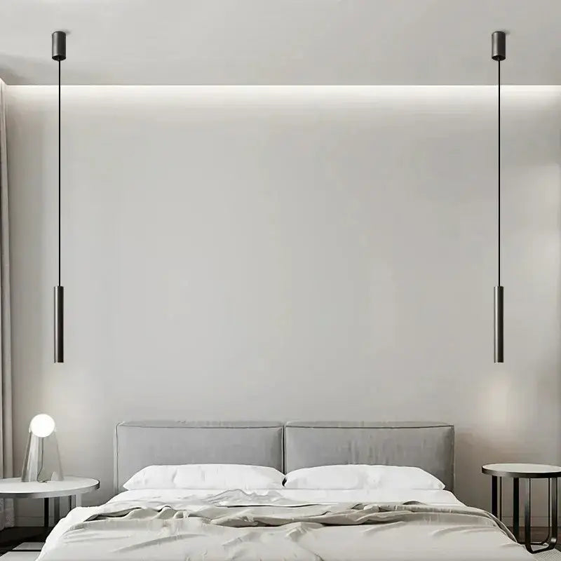 Two sleek matte black cylindrical decorbites elegant brass pendant lights hang symmetrically above a bed