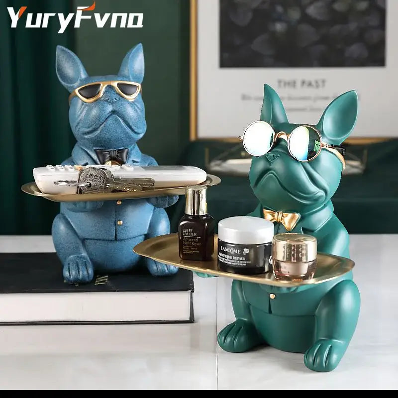 Two stylized blue and teal bulldog figurine coin banks with sunglasses and bow ties holding gold trays for home decor