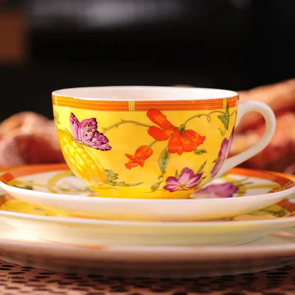 A vibrant yellow porcelain teacup with butterfly kitchen tableware design featuring floral accents and orange trim