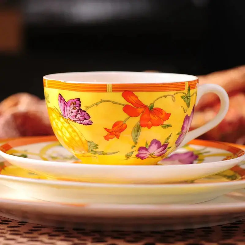 A vibrant yellow porcelain teacup with butterfly kitchen tableware design featuring floral accents and orange trim