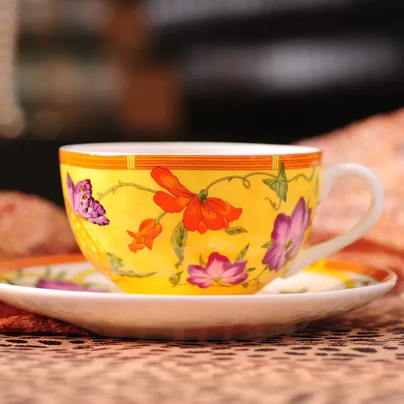 A vibrant yellow porcelain teacup with floral and butterfly designs and a gold rim from butterfly kitchen tableware set