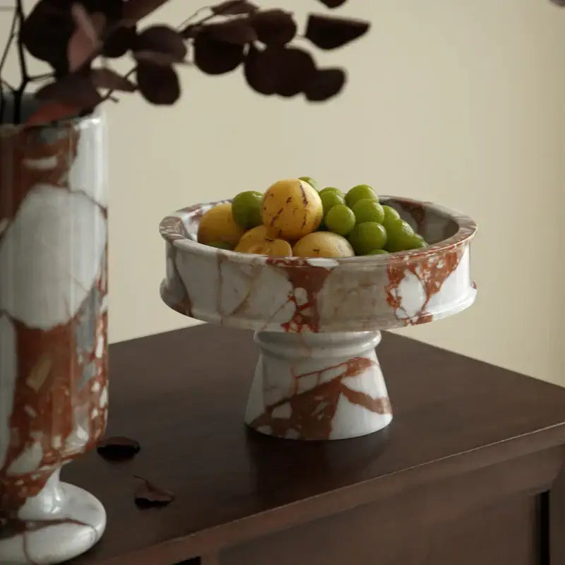 Elegant calacatta red marble vase with white and rust pedestal bowl holding green grapes and yellow citrus fruit decorbites calacatta red